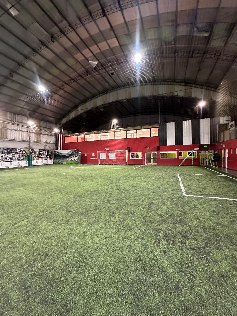 Cancha techada real de Complejo Juventus, con césped sintético y paredes rojas